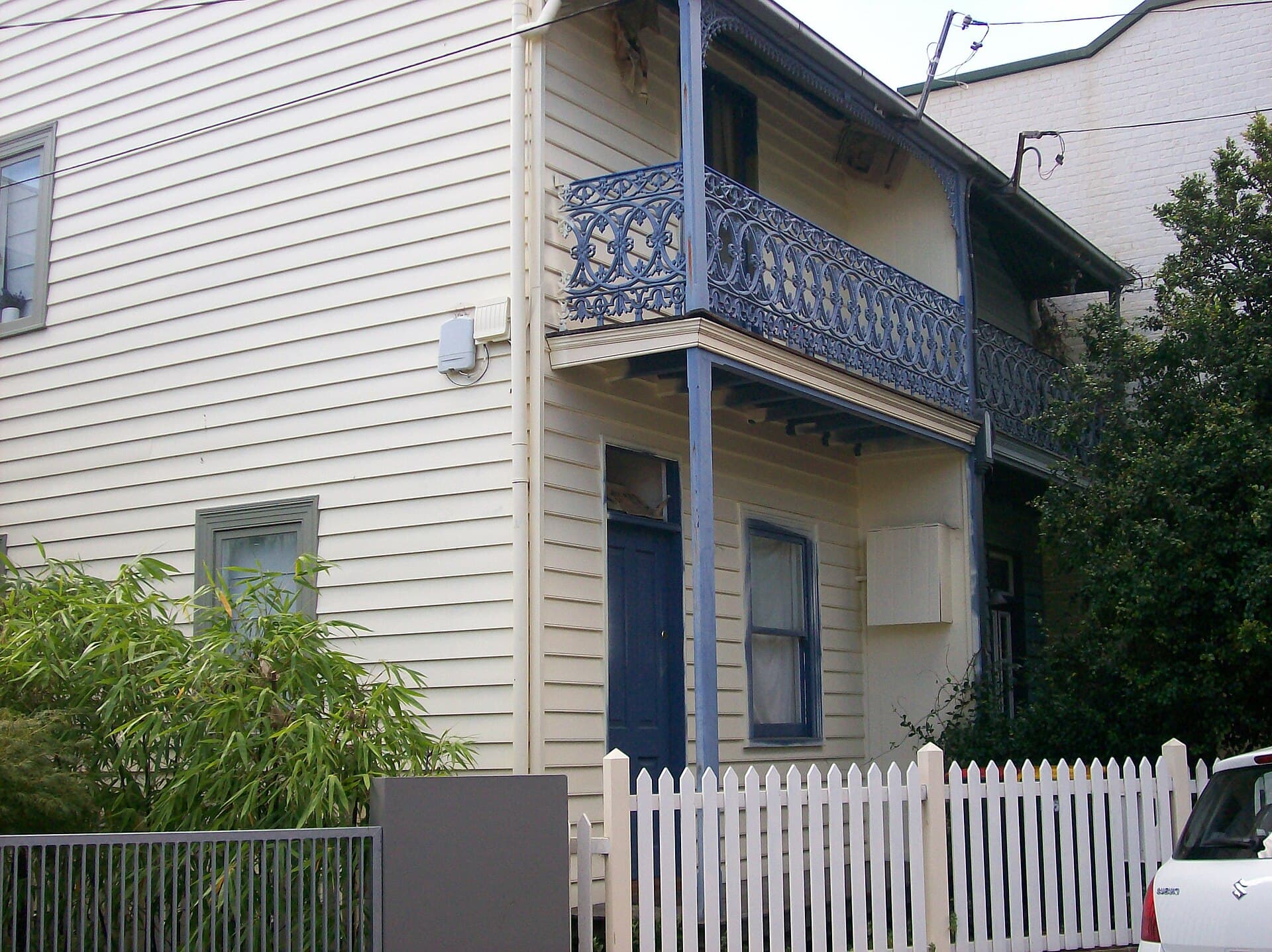 A row of weatherboard Victorian terraces with a corrugated-iron roof